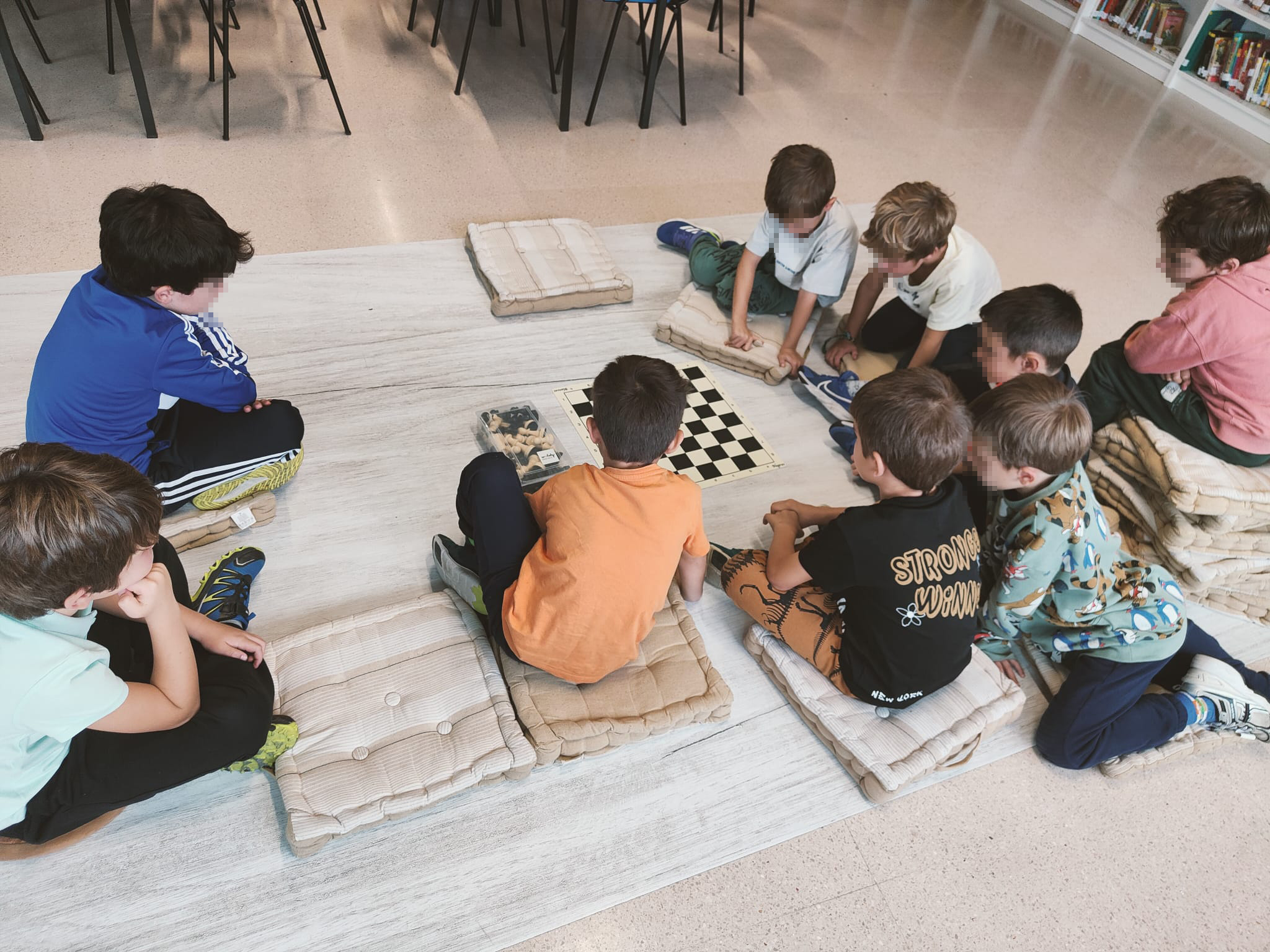 Niños jugando ajedrez educativo sentados en cojines en el suelo